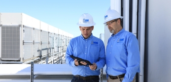 Two men discussing business while holding an ipad on a commercial rooftop building.